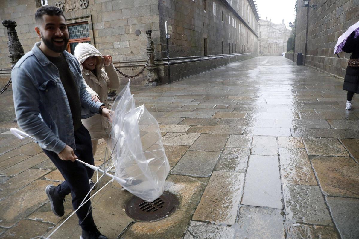 Joven con un paraguas roto en Santiago como consecuencia de las rachas de viento