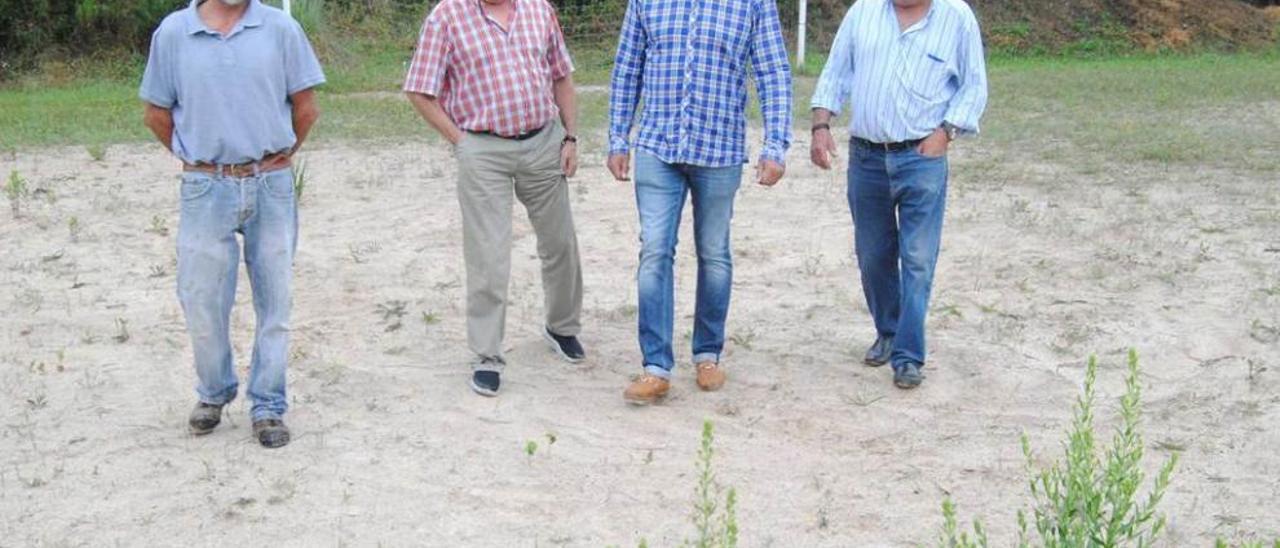 Los directivos Carlos Alonso, Manuel Díaz y Javier Noval, y el alcalde de barrio de Santiago de Arenas, Cándido Martínez, en el campo de arena que han dejado de utilizar por sus malas condiciones.