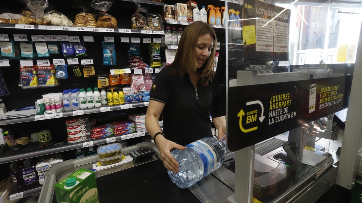 La empleada de una tienda de Novallas cobra una garrafa de agua embotellada, hace dos semanas.