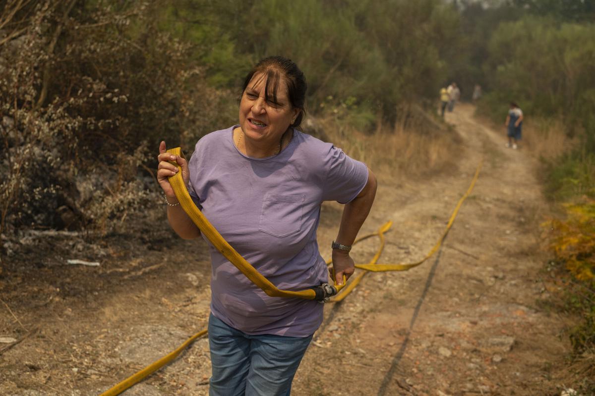 Una vecina de Vilar de Condes colabora en las labores de extinción del incendio forestal en Carballeda de Avia (Ourense), este sábado