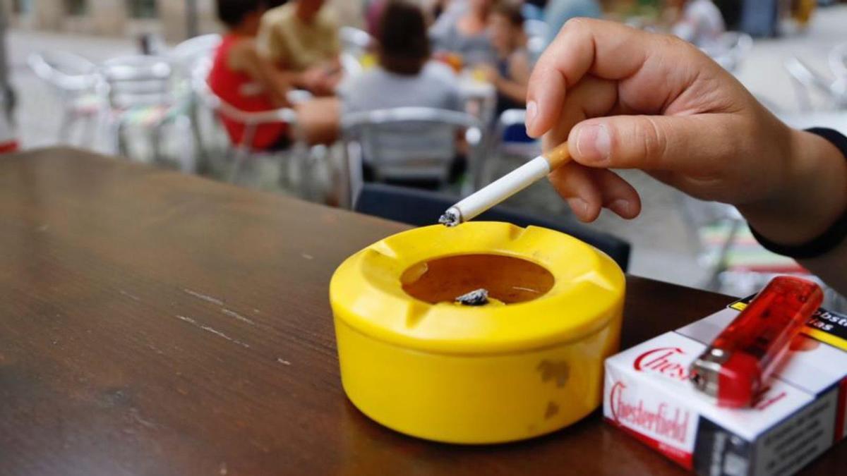 Un cliente fuma un cigarrillo en una terraza.