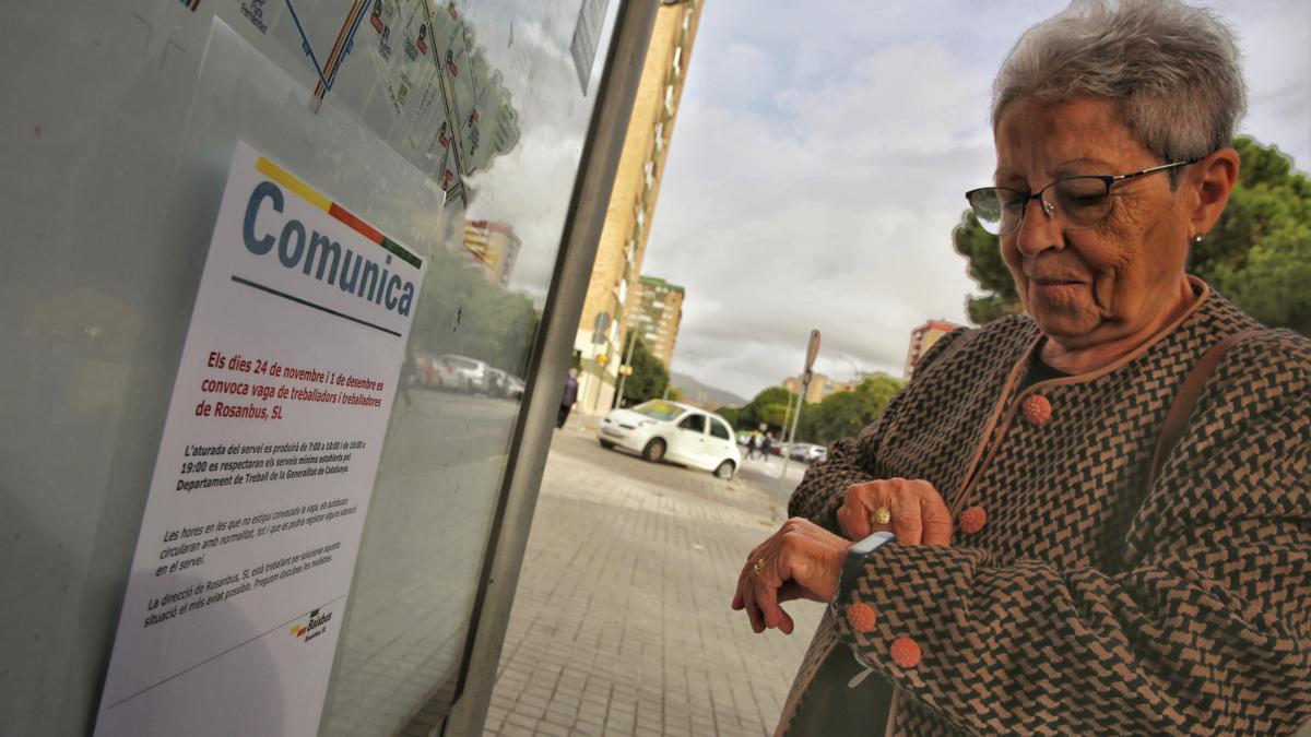 Imagen de archivo de una mujer que consulta el reloj en una parada de autobús de L'Hospitalet durante una huelga en L'Hospitalet.