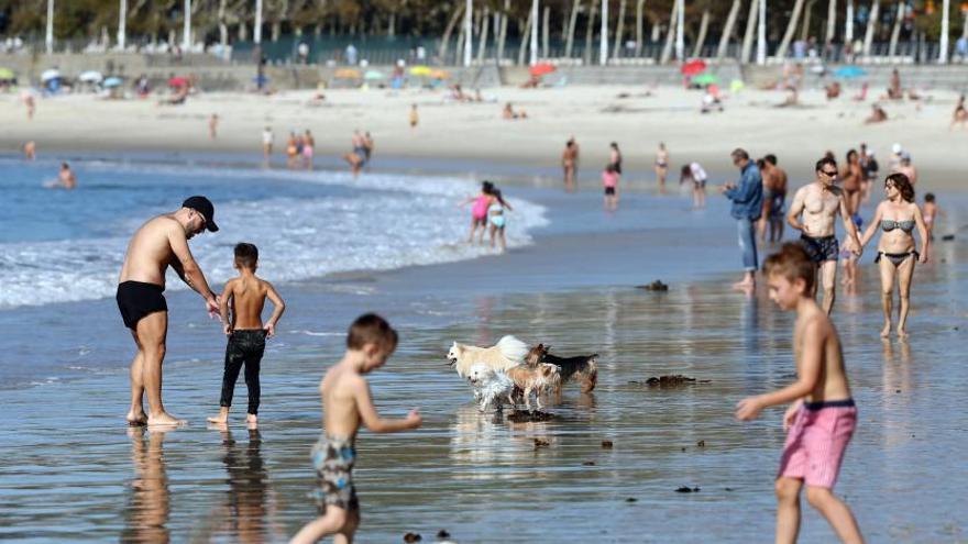 Bañistas disfrutando del puente en la playa de Samil.