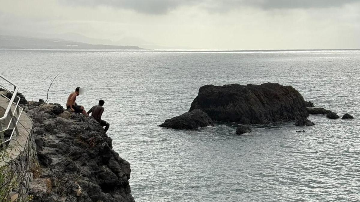 Dos jóvenes menores de edad se disponen a lanzarse al agua desde un risco en la zona entre La Puntilla y El Confital