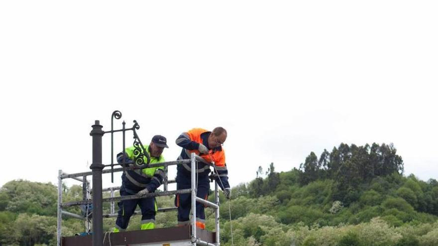 Tres operarios renuevan las farolas del puente que une Sama y La Felguera, en una operación realizada el año pasado.