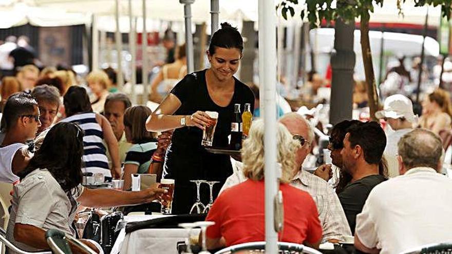 Una camarera sirve a los clientes sentados en una terraza.