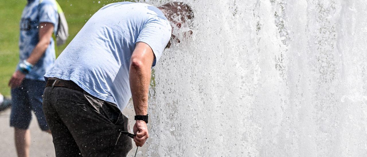 Un hombre se refresca en una fuente