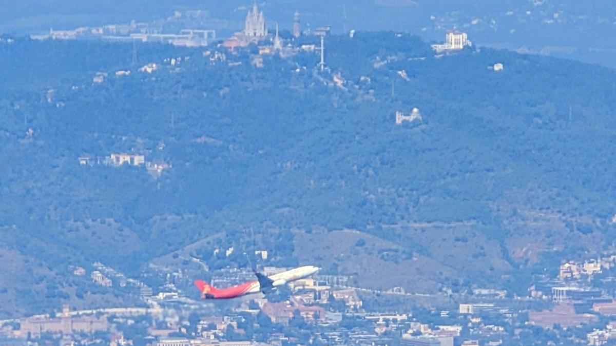 Un avión de Iberia sobrevuela Barcelona, con el Tibidabo al fondo.