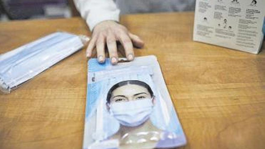 Una farmacéutica muestra un paquete de mascarillas.