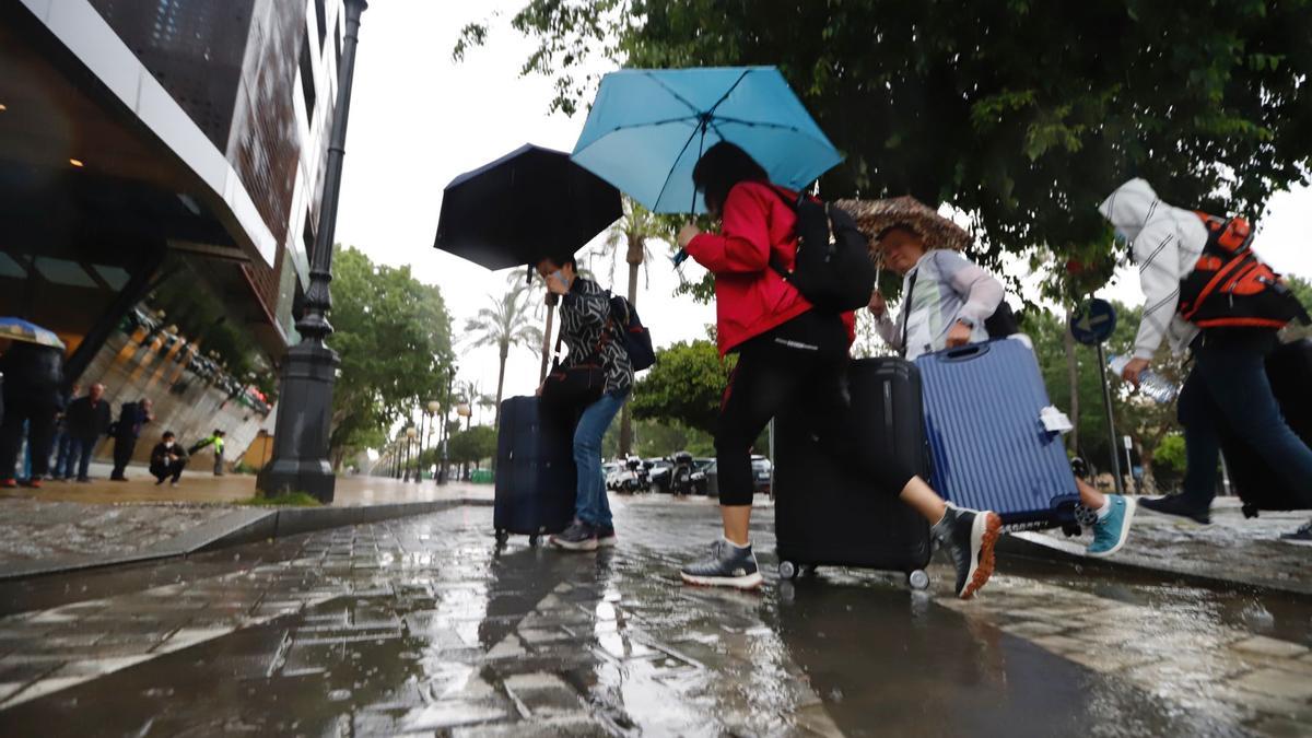 Turistas corren con sus maletas bajo la lluvia para acceder a un hotel de Córdoba, este martes.