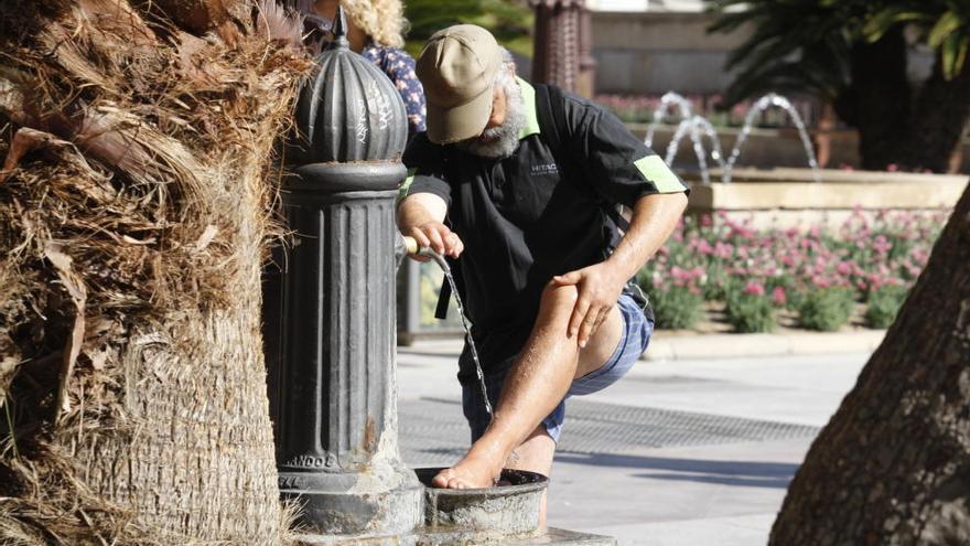 Un hombre se refresca los pies en una fuente en Murcia.