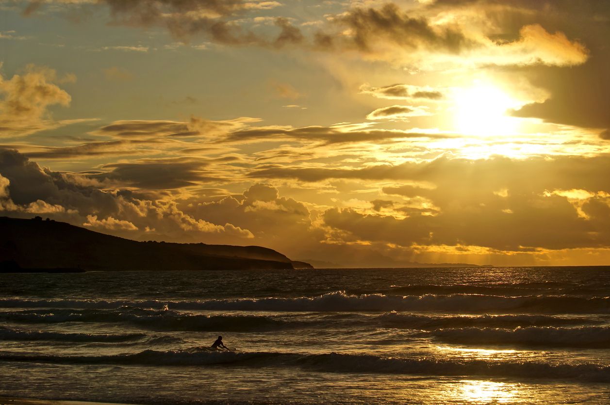 Una chica haciendo surf en San Vicente de la Barquera al atardecer