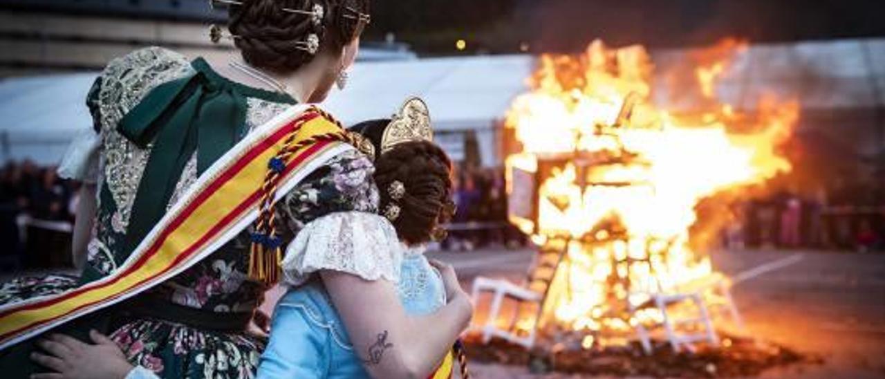 Dos falleras se abrazan ante la «cremà» de la falla.