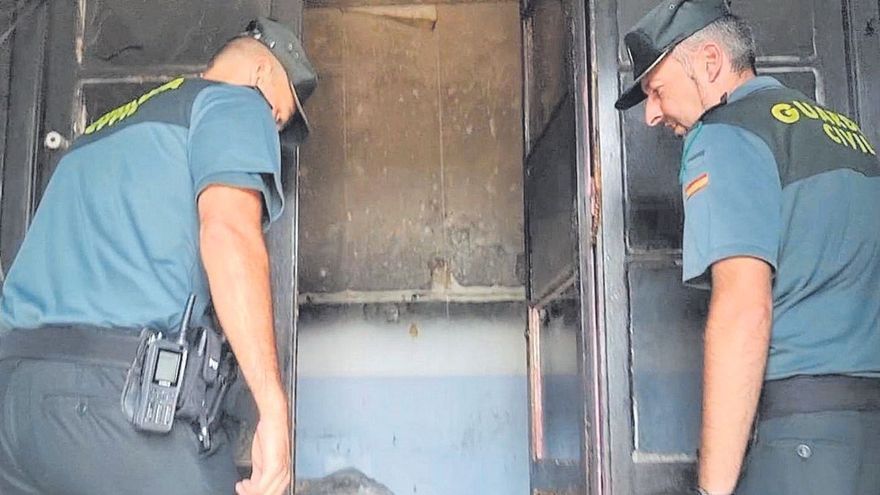 El sargento Aitor Suárez y el guardia José Ramón Camoria inspeccionan el interior de la casa que ardió en Pravia (Asturias).