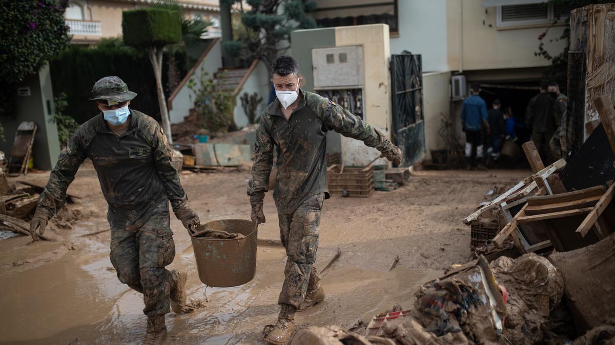 Dos militares ayudan a limpiar los estragos ocasionados por la DANA.