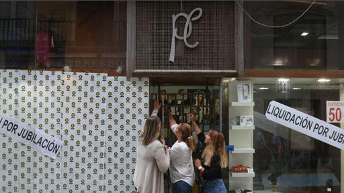 Belén Pérez-Cea y dos empleadas echando por última vez el candado a la puerta de entrada del negocio centenario en 2014