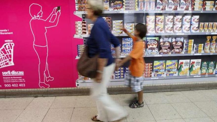 Una mujer y un niño realizan la compra en un supermercado. / gustau nacarino