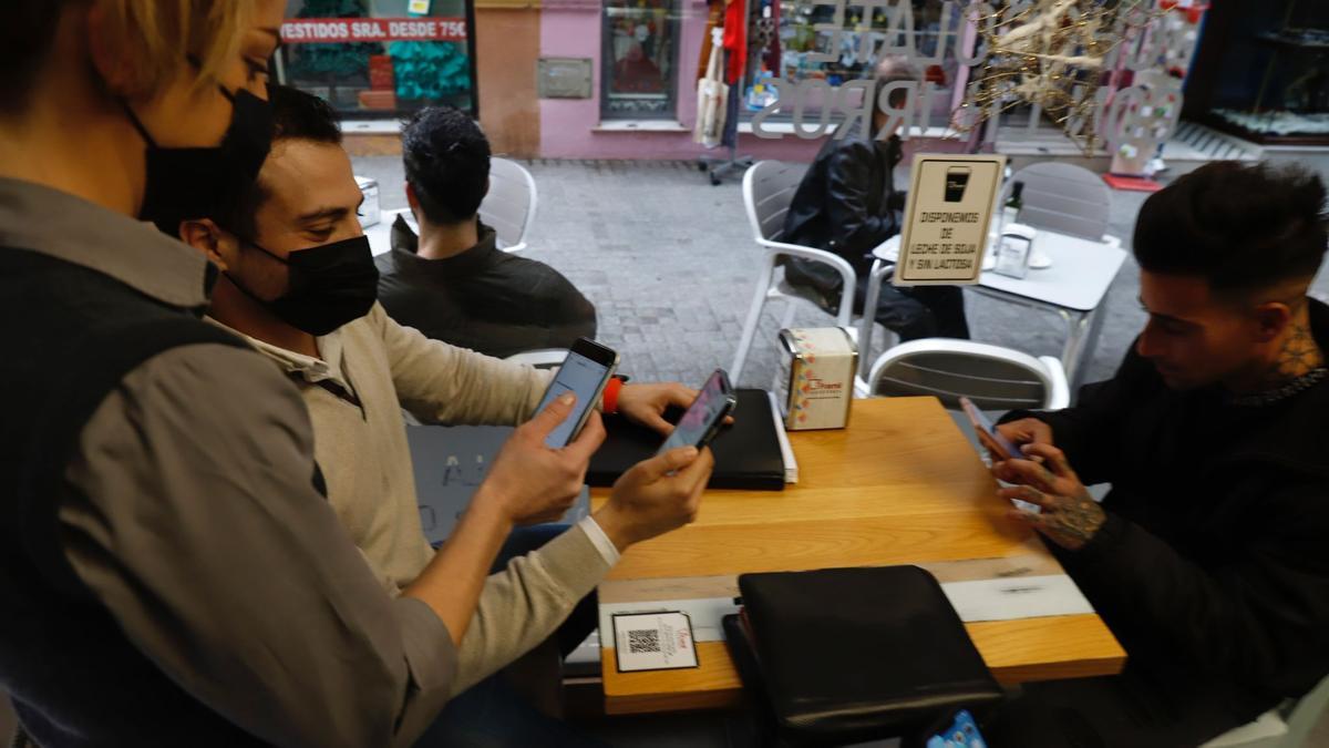 Una camarera consulta el pasaporte covid en una cafetería del Centro de Málaga.