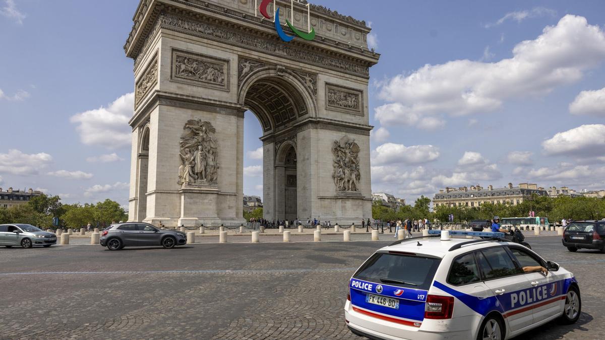 Un coche de la policía francesa circula junto al Arco de Triunfo de París.