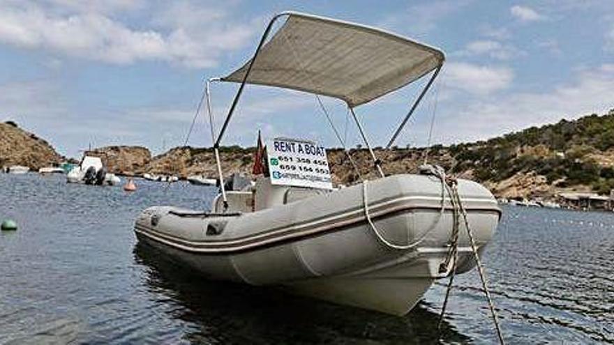 Una de las embarcaciones en alquiler en Cala Vedella con un cartel anunciador.