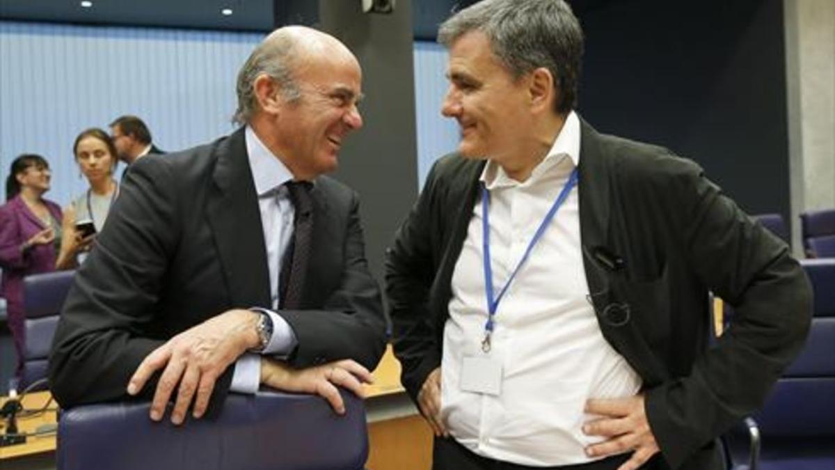 Luis de Guindos conversa con su homólogo griego, Euclides Tsakalotos, ayer en el Eurogrupo, en Luxemburgo.