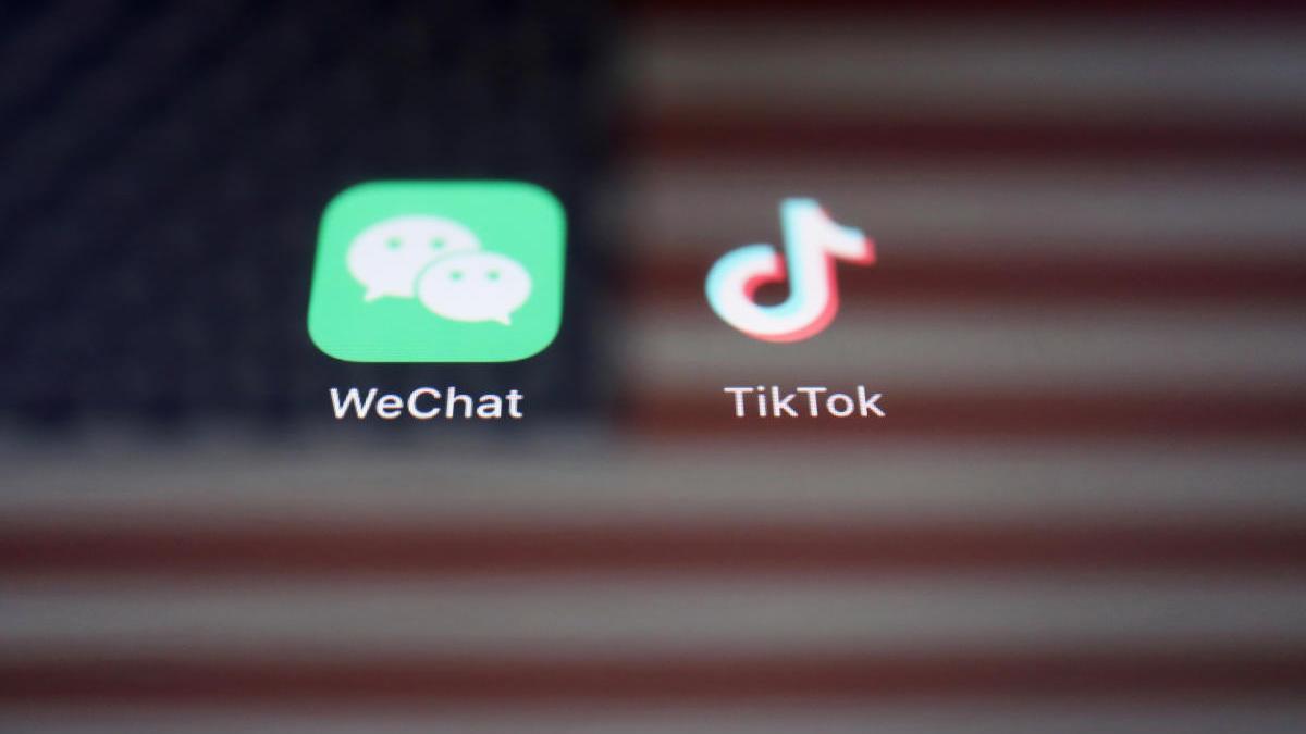 Los logos de TikTok y WeChat reflejados sobre una bandera de EEUU