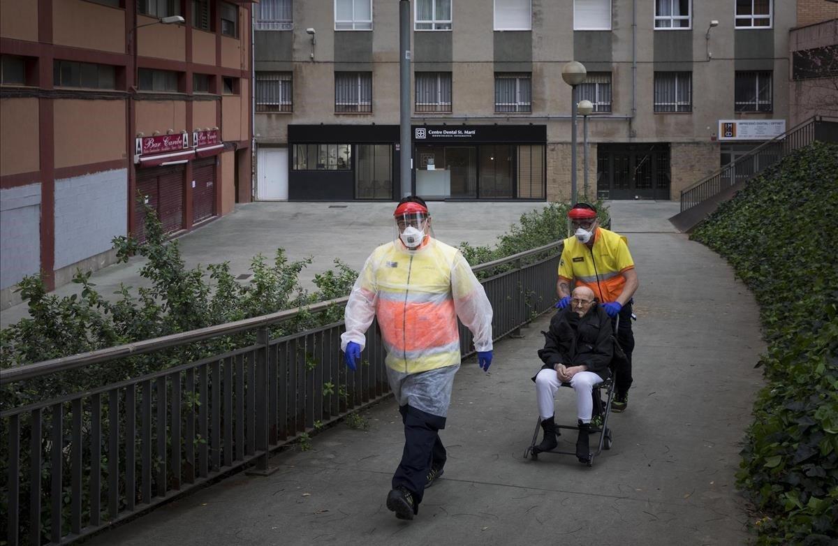 Personal sanitario del SEM trasladan a un anciano con síntomas de covid-19 desde su domicilio, en el barcelonés barrio de La Verneda, al Hospital del Mar.