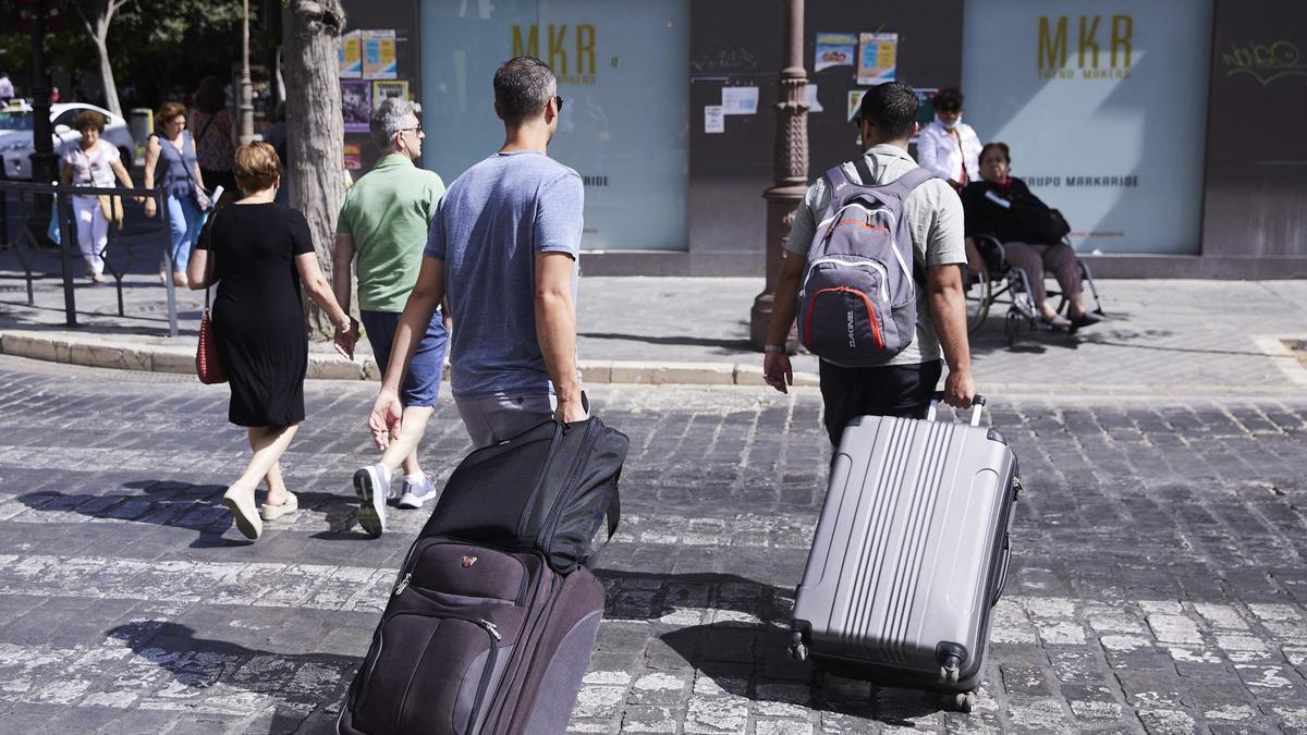 Dos turistes, amb maletes, creuen un pas de vianants