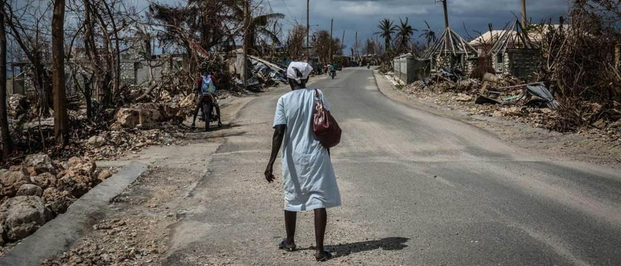 Una mujer camina en mitad de una localidad en ruinas.