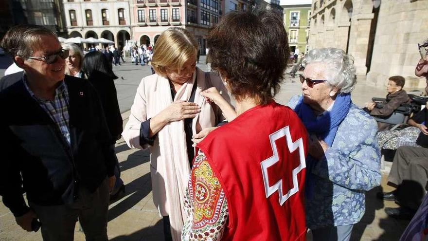 Una voluntaria de Cruz Roja coloca a la Alcaldesa una pegatina en agradecimiento por su donativo.