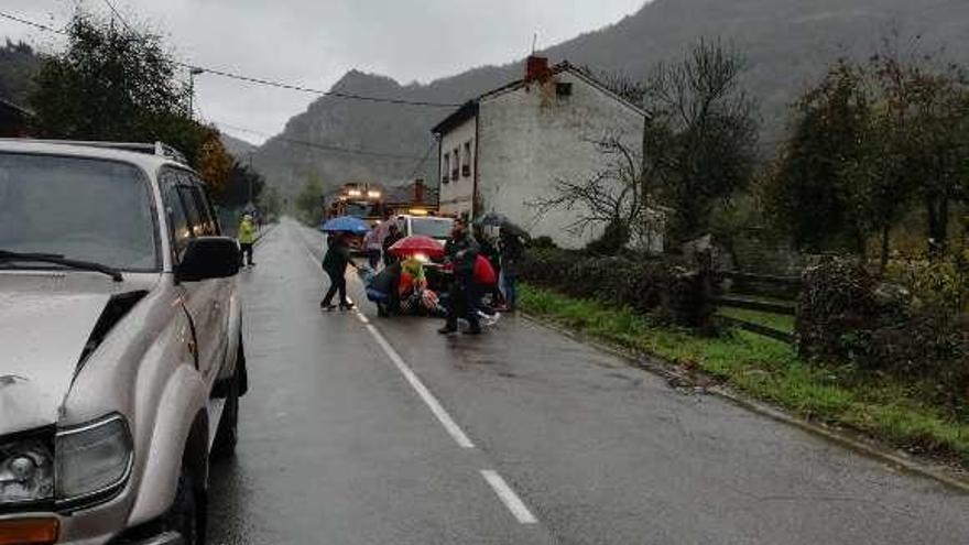 Un grupo de personas atiende a la mujer atropellada en el lugar del suceso, en Levinco, con el coche en primer término.