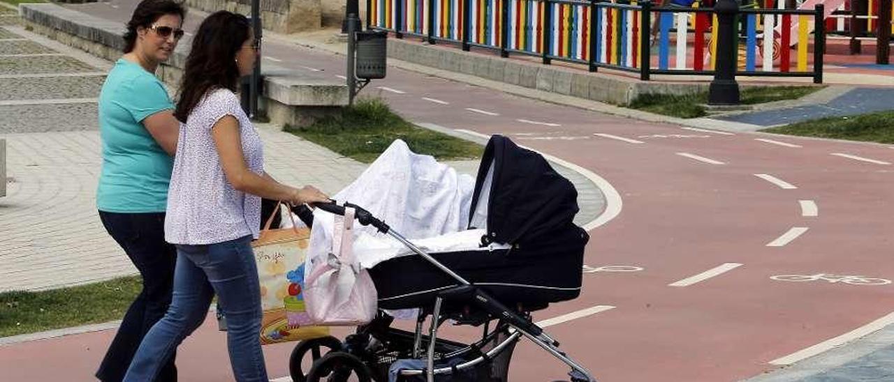 Dos mujeres arrastran a dos carritos de bebé en el paseo de Bouzas. // Marta G. Brea