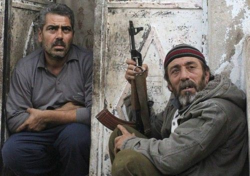 Se esconde un residente en una puerta mientras habla con un miembro del Ejército Libre de Siria que pasa por su casa durante los enfrentamientos con las fuerzas progubernamentales en la ciudad de Harem 30 de octubre 2012 foto de archivo.