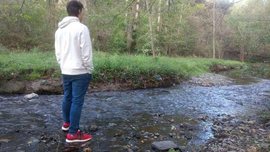 Un joven observa el curso del río Angueira, donde este año no se podrá pescar cangrejo.