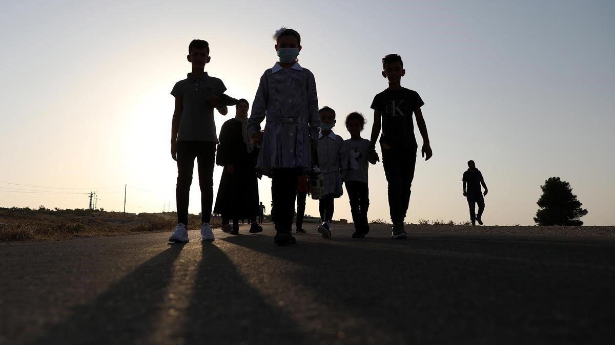 Un grupo de niños palestinos se dirigen a la escuela en el primer día del curso del nuevo año escolar, en Cisjordania, al sur de Hebrón.