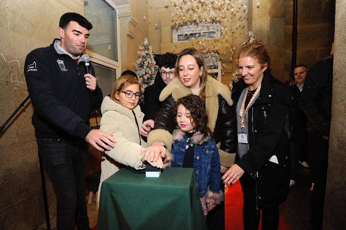 O alcalde da Estrada, Gonzalo Louzao, premendo o botón para acender o alumedo de Nadal con nenos e nenas de Asanog.