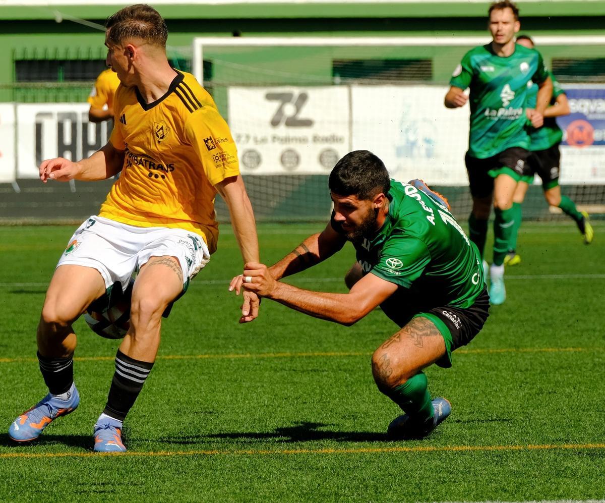 Iván Fernández, sujetado por un jugador del equipo palmero.