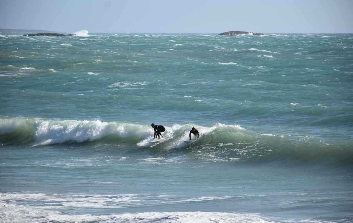 Dos jóvenes hacen surf en ses Salines, con un fuerte oleaje. | C. N.