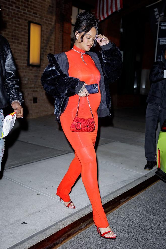 Rihanna vestida con un mono-falda naranja y chaqueta negra