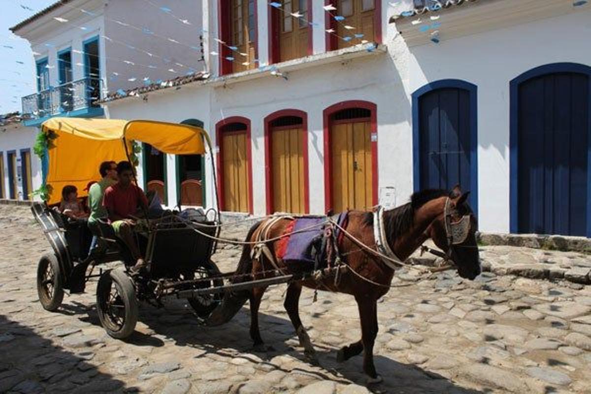 Turistas pasean por las calles de Parati en un carro tirado por caballos.