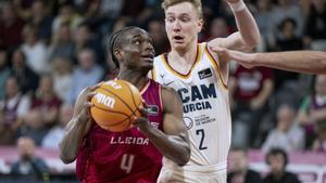 El escolta nigeriano de Hiopos Lleida, Caleb Agada (i), entra a canasta ante el alero estonio de UCAM Murcia, Sander Raieste, durante el encuentro correspondiente a la fase regular de la Liga Endesa que disputaron en el pabellón Barris Nord de Lleida. 