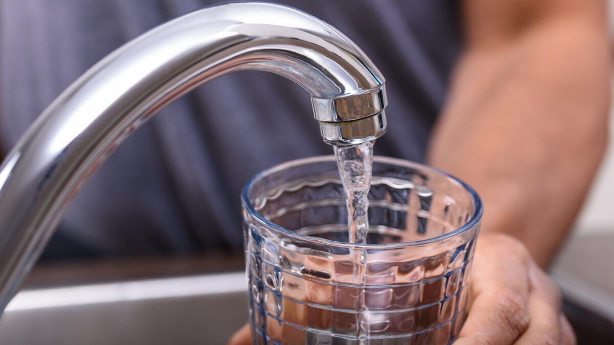 Una persona se sirve agua del grifo en un vaso.