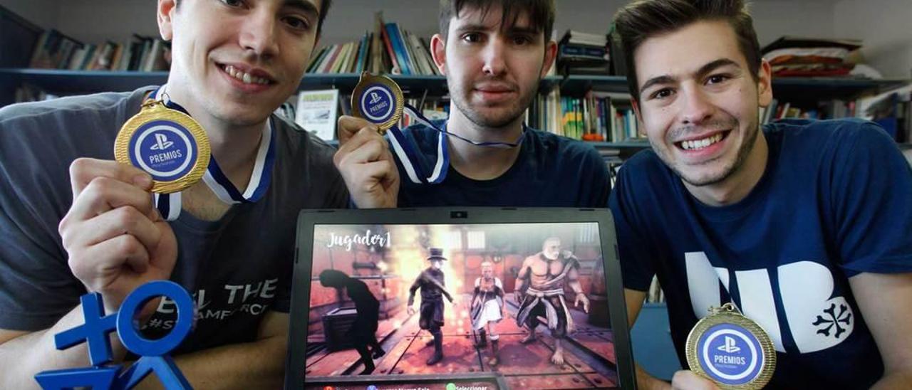 Orián Holguera, Rubén Digón y Pablo Artime muestran sus medallas y el trofeo conseguidos y la pantalla de inicio de su videojuego.