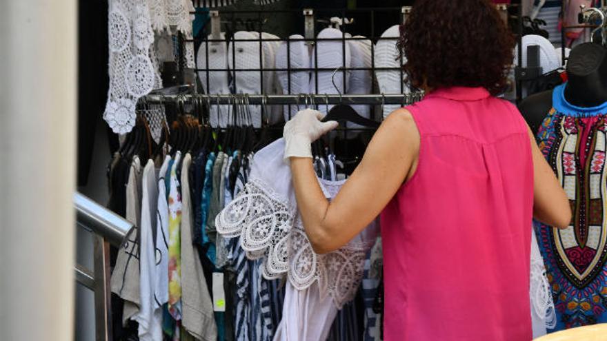 Una trabajadora de una tienda de Meloneras manipula la ropa, ayer, con guantes.