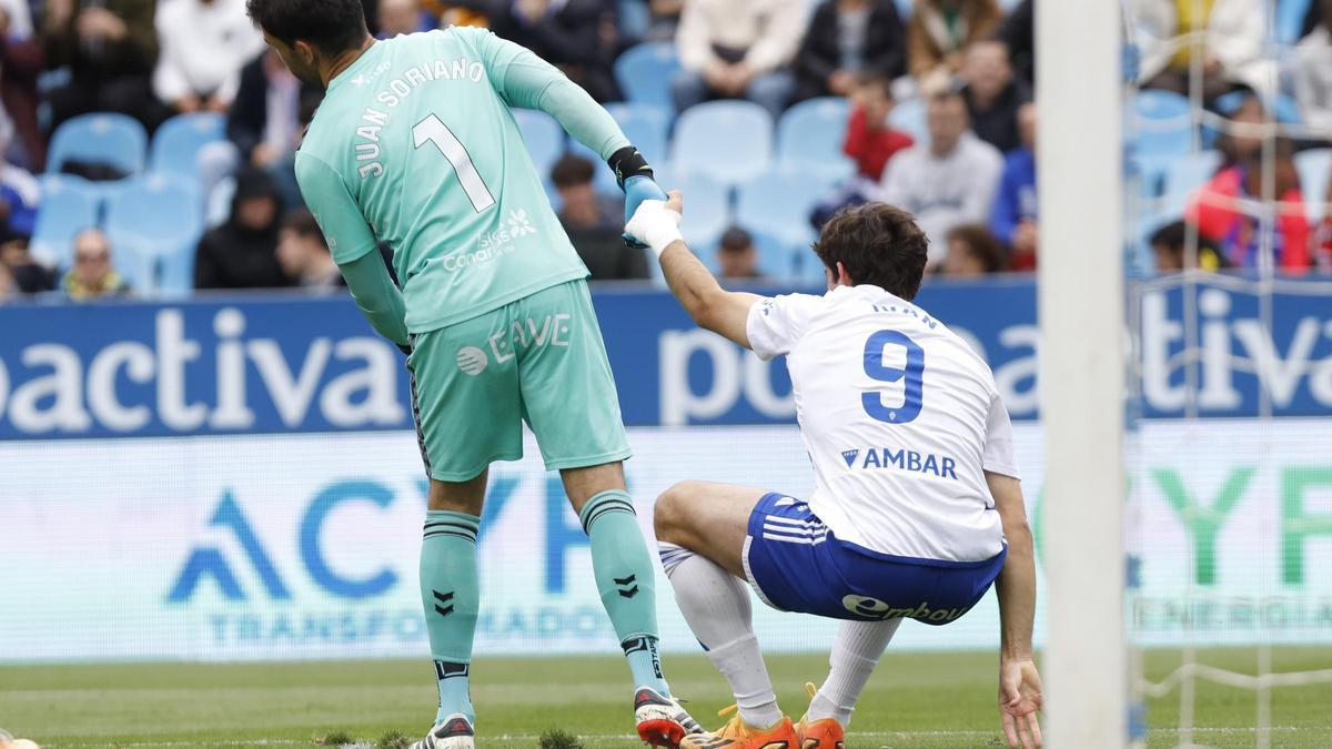 El meta del Tenerife Juan Soriano ayuda a levantarse a Azón en el partido en La Romareda.