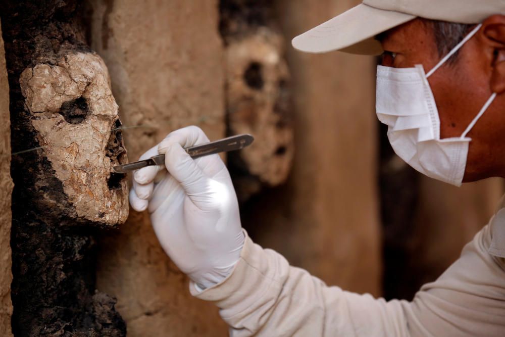An archaeologist cleans a wooden mask of the ...