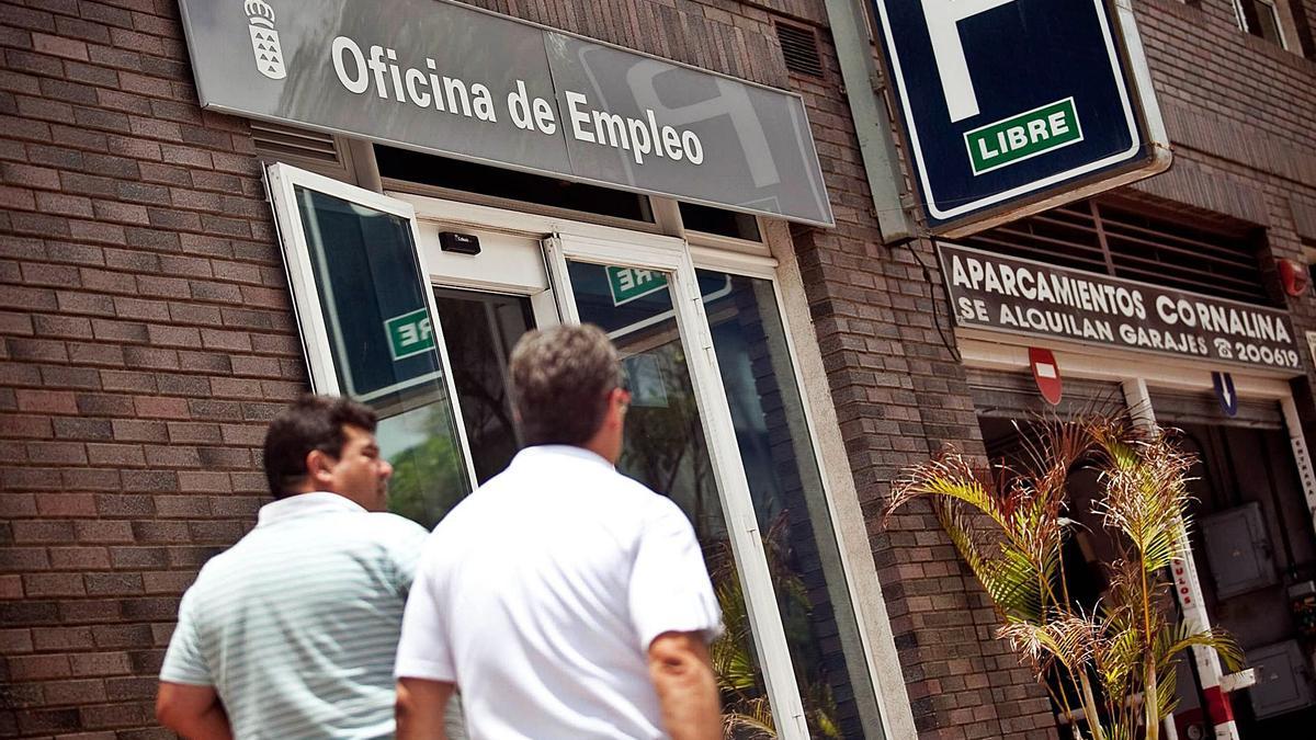 Dos hombres pasan ante la oficina de empleo de Tomé Cano, en Santa Cruz de Tenerife.