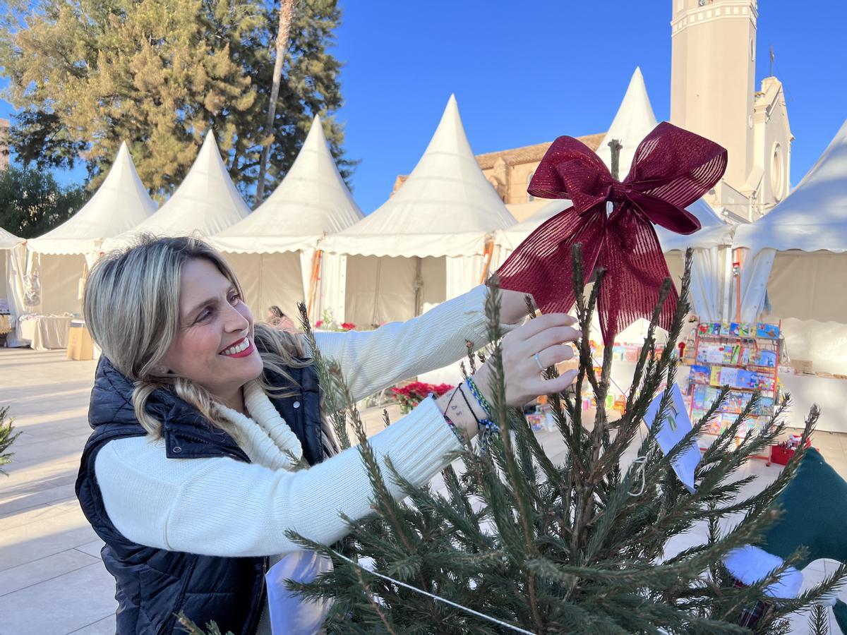 Marta Barrachina coloca un adorno en un árbol de Navidad.
