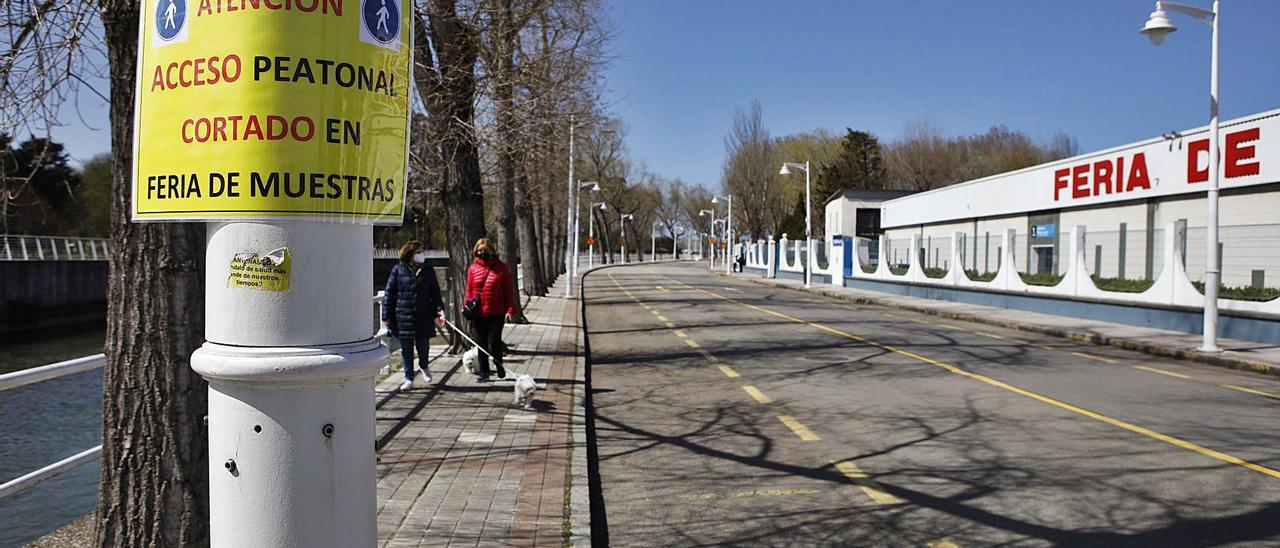 Viandantes por el paseo del Doctor Fleming, ayer, a la altura de la zona del recinto ferial más cercana al parque de Hermanos Castro, al fondo a la derecha, donde comenzará el trazado del nuevo vial. | Ángel González