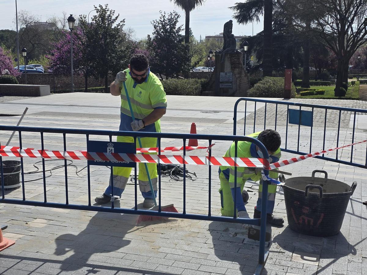 Dos trabajadores municipales reparan un acerado en Badajoz.